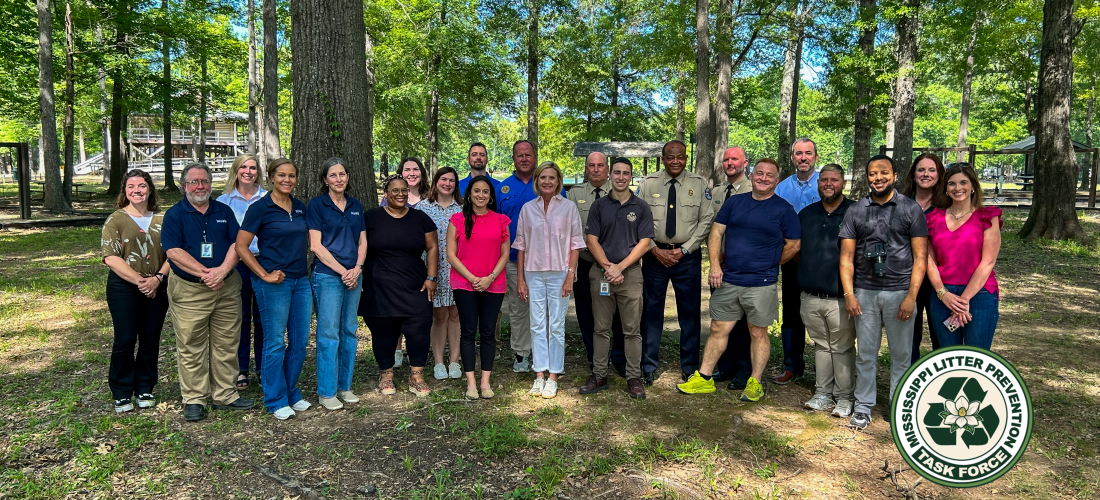 A group of people standing for a photo in the park with green trees